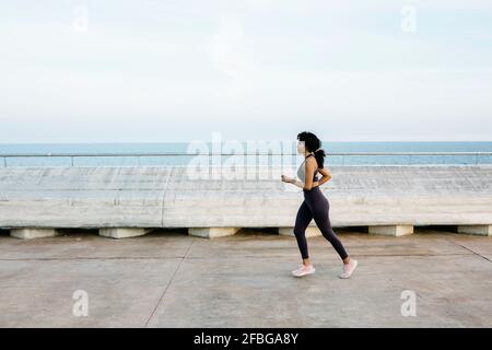 Weibliche Athletin mit mittlerem Erwachsenenalter, die auf der Brücke läuft Stockfoto