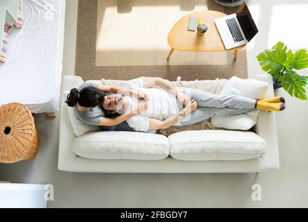 Entspannter Mann, der auf dem Schoß der Frau im Wohnzimmer liegt Zu Hause Stockfoto
