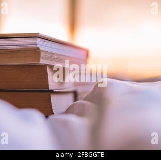 Ein Stapel von mehreren Büchern liegt auf dem Bett zu Hause. Genießen Sie das Lesen wunderbarer Bücher in der Freizeit. Toller Entspannender Hobby. Stockfoto