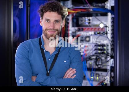 Männlicher IT-Spezialist mit gekreuzten Armen, der im Rechenzentrum steht Stockfoto