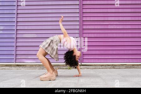 Junge Tänzerin, die sich an einer bunten Wand nach hinten beugt Stockfoto