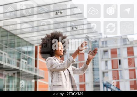 Geschäftsfrau Blick auf Karte über futuristische transparente digitale Tablet mit Symbole im Freien Stockfoto