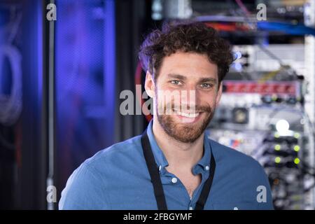 Glücklicher männlicher IT-Techniker, der im Rechenzentrum steht Stockfoto