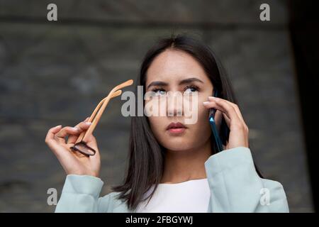 Weibliche Unternehmerin schaut weg, während sie am Telefon spricht Stockfoto