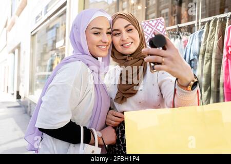 Weibliche arabische Freunde in Hijabs, die Selfie über das Smartphone machen Beim Einkaufen in der Stadt Stockfoto