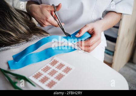 Physiotherapeutin schneidet elastisches therapeutisches Band Stockfoto
