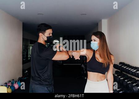 Sport Menschen tragen schützende Gesichtsmaske Gruß mit Ellenbogen Beule Im Fitnessstudio Stockfoto