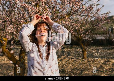 Junge Frau lacht, während sie den Mandelbaum hält Stockfoto