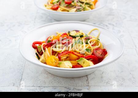 Spaghetti mit gegrilltem Gemüse, Paprika, Zucchini, Avocado, Tomaten und Koriander Stockfoto