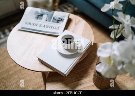 Kaffee im Buch von Zeitung auf Holztisch zu Hause Stockfoto