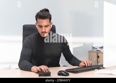 Männlicher Finanzberater, der am Rechner am Arbeitsplatz berechnet Ort Stockfoto