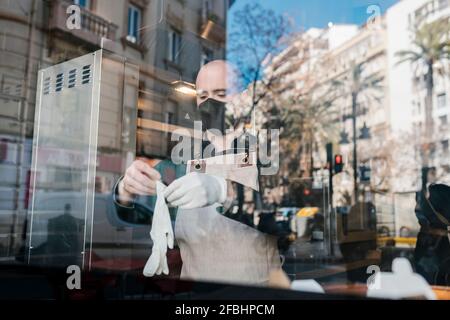 Mann mit Schutzhandschuhen durch Glas im Restaurant gesehen Stockfoto