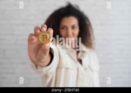 Junge Frau mit Bitcoin vor der Wand Stockfoto