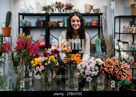 Junge weibliche Floristin arrangiert Blumen im Geschäft Stockfoto