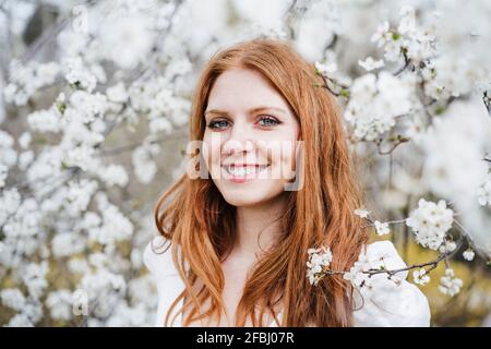 Glückliche Frau, die inmitten eines weißen Mandelbaums steht Stockfoto