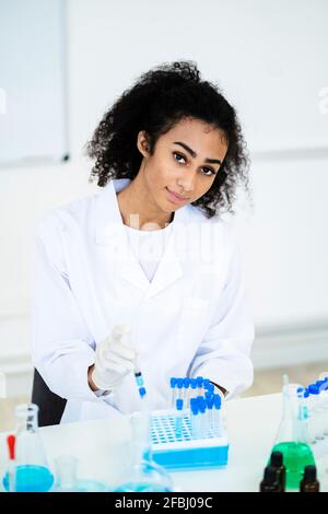 Junge Forscherin hält Spritze an Reagenzglas während der Arbeit Im Labor Stockfoto