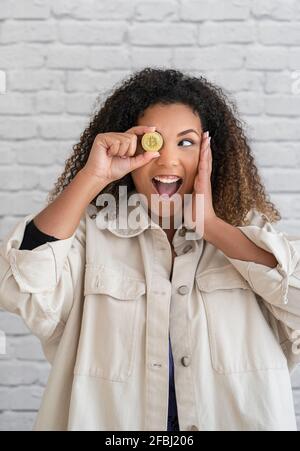 Überraschte junge Frau, die seitwärts schaute, während sie die Augen durch Kryptowährung deckte Stockfoto
