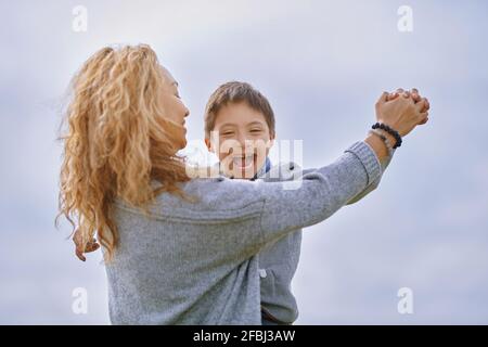 Mutter hält beim Tanzen die Hand eines Sohnes mit Down-Syndrom Stockfoto