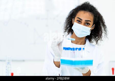 Forscherin, die während einer Pandemie Mikrotiterplatten im Labor hält Stockfoto