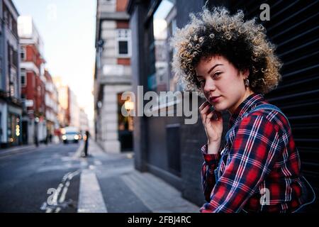 Junge Frau mit lockigen Haaren vor dem Verschluss Stockfoto