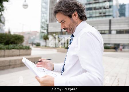 Konzentrierter männlicher Architekt, der an Blaupause arbeitet Stockfoto