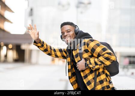 Lächelnder junger afroamerikanischer Mann, der die Fahrt anhagelt Stockfoto