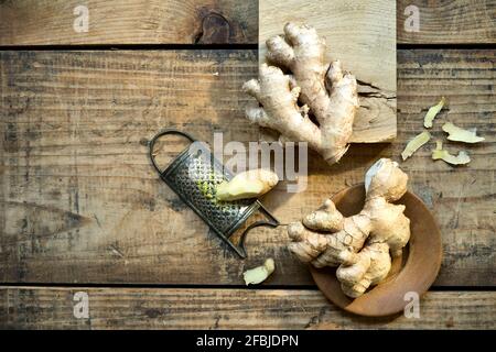 Ingwerwurzeln und alte Reibe liegen auf Holzoberfläche Stockfoto