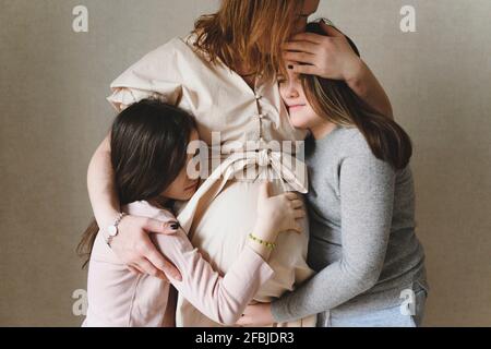 Schwangerin umarmt Töchter zu Hause Stockfoto