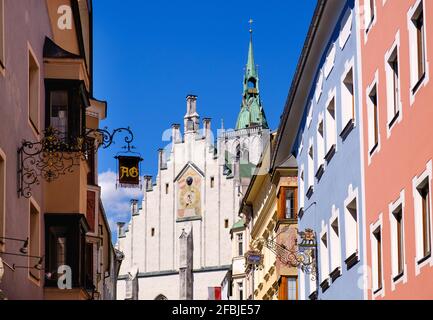 Franz-Josef-Straße mit Zunftschildern und Pfarrkirche im Hintergrund, Schwaz, Tirol, Österreich Stockfoto