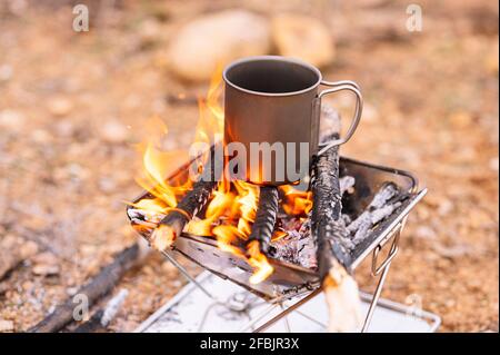 Kaffeebecher auf brennendem Brennholz Stockfoto