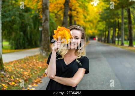 Porträt einer lachenden Frau mit Herbstlaub avenue Stockfoto