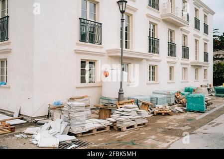 Fassade eines im Bau befindlichen Hauses. Baustoffe liegen auf Holzpaletten Stockfoto