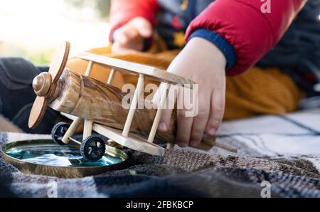 Junge spielt mit Holzhubschrauber über Lupe auf Decke Stockfoto