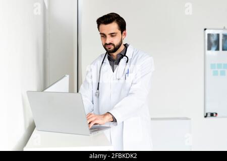 Schöner männlicher Arzt mit Laptop im Krankenhaus Stockfoto