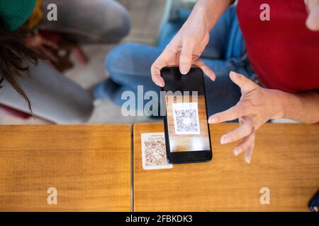 Frau scannt QR-Code über Smartphone im Café Stockfoto