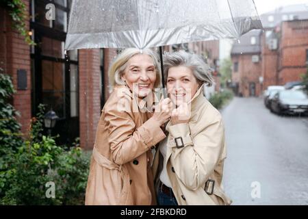 Fröhliche Frauen unter dem Regenschirm genießen Regentag Stockfoto