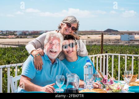 Lächelnder Junge, der sich mit den Großeltern während des Mittagessens amüsieren kann Stockfoto
