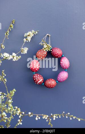 Blühende Zweige und DIY-Kranz aus rot getupftem Ostern Eier Stockfoto