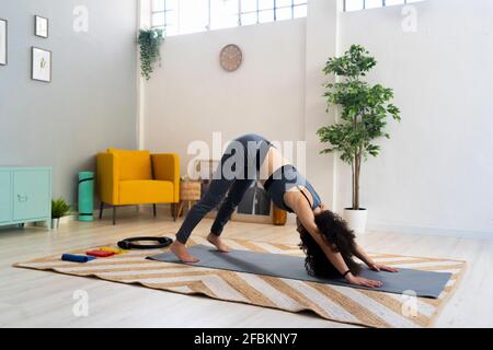 Frau übt zu Hause nach unten schauende Hundestellung Stockfoto