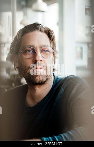 Nachdenklicher männlicher Besitzer, der im Café wegschaut Stockfoto
