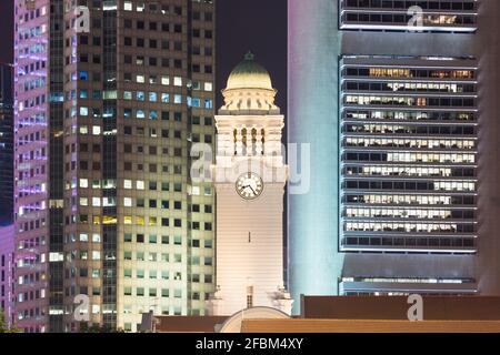 Singapur, Uhrenturm des Victoria Theatre und Konzerthalle bei Nacht mit Wolkenkratzern im Hintergrund Stockfoto