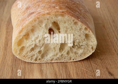 Frisches Brot auf Schneidebrett, Speisen aus der Nähe, köstliches hausgemachtes, in Scheiben geschnittenes italienisches Ciabatta-Brot auf Holzschneidebrett Stockfoto