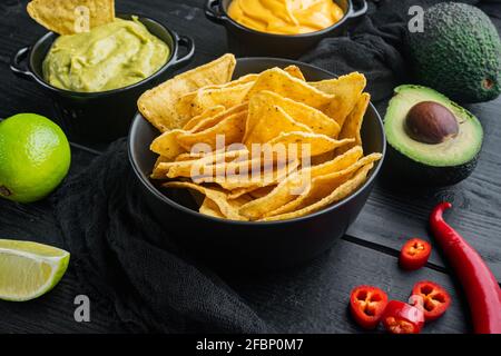 Verschiedene Dips und Saucen für Nacho, auf schwarzem Holzhintergrund Stockfoto