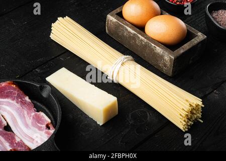 Traditionelle Italienische Pasta Carbonara Zutaten. Speck, Spaghetti, Parmesan und Pecorino-Käse, Ei, Knoblauch-Set, auf schwarzem Holzhintergrund Stockfoto