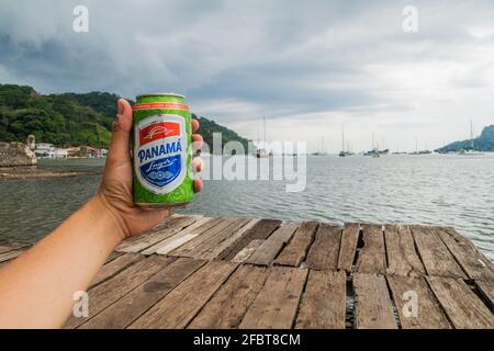 PORTOBELO, PANAMA - 28. MAI 2016: Die menschliche Hand hält eine Dose Panamabier auf einem hölzernen Pier im Dorf Portobelo, Panama Stockfoto