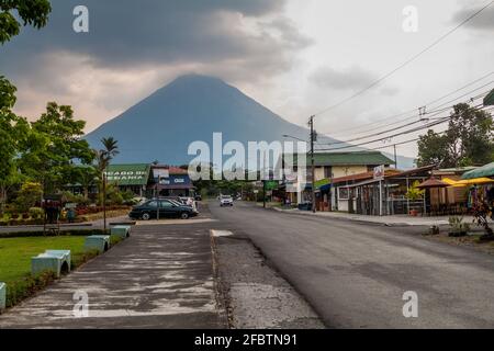 LA FORTUNA, COSTA RICA - 8. MAI 2016: Der Vulkan Arenal ragt hinter dem Dorf La Fortuna hoch. Stockfoto
