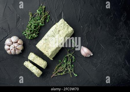 Portion Kräuterbutter mit Schnittlauch, Basilikum, Oregano, Petersilie-Set, auf schwarzem Stein-Hintergrund, mit Platz für Text Stockfoto