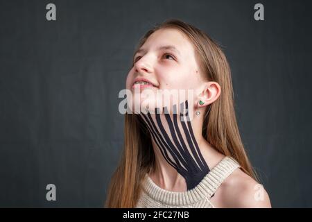 Mädchen mit schwarz gestreiftem Kinesiologieband auf dem Hals platziert Stockfoto