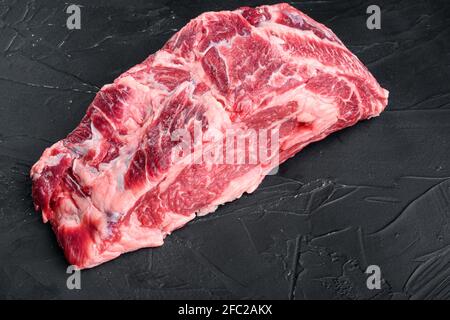 RAW Rib Eye Beef Steak aus marmoriertem Fleisch, komplett geschnitten, auf schwarzem Stein Hintergrund Stockfoto