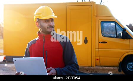 Ansicht des Bauingenieurs mit Schutzhelm, der mit einem Laptop vor Ort steht, in der Taille nach oben. Hochwertige Fotos Stockfoto
